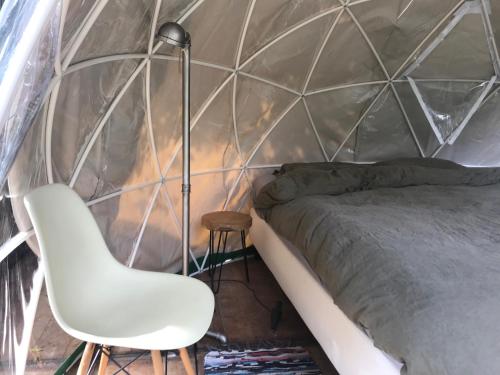 ein Schlafzimmer mit einem Bett, einer Lampe und einem Stuhl in der Unterkunft Vintage Dome Igloo tent, Lange Haven Schiedam in Schiedam