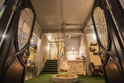 a hallway with green carpet and a staircase with a chandelier at Tamajun Hotel in Chanthaburi