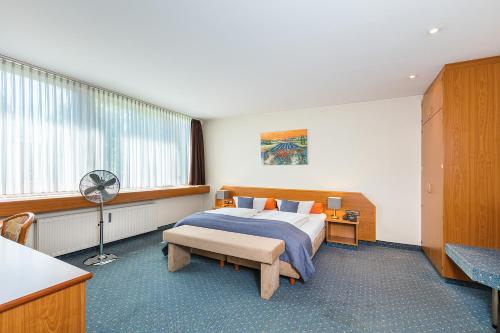 a bedroom with a bed and a desk with a fan at Hotel Servatius in Cologne