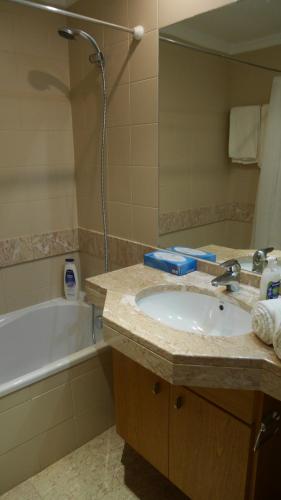a bathroom with a sink and a tub and a mirror at Jasmineiro - Palms Palace Apartment in Funchal