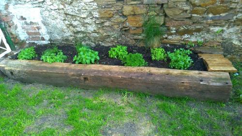 a wooden planter with plants in front of a stone wall at Chalupa u kostela in Lukov