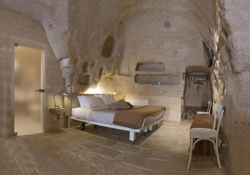 a bedroom with a bed in a stone wall at Thymus Residence nei Sassi in Matera