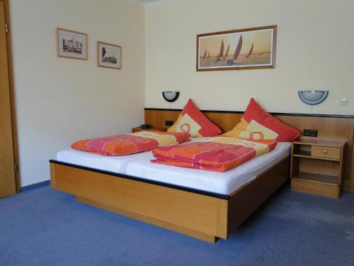 a bedroom with a bed with red and orange pillows at Pension Am Wiesengrund in Detern