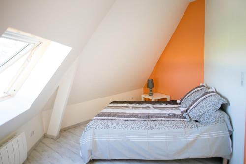 a bedroom with a bed with an orange wall at Le Manège in Varengeville-sur-Mer