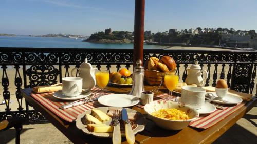 a table with breakfast food on a balcony with a view at Hotel Villa Reine Hortense in Dinard