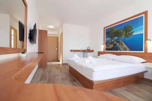 a bedroom with a large white bed with a large painting on the wall at Villa Amorena - Adults Only in Bol
