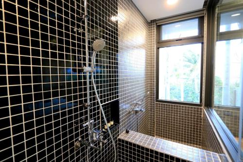 a black tiled bathroom with a shower and a window at 墾丁 住在Zhuzai in Checheng