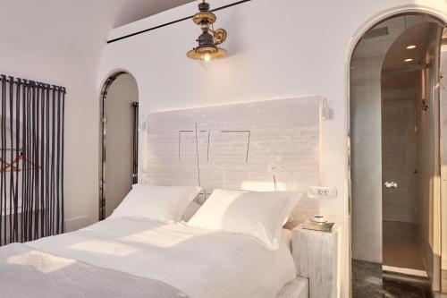a bedroom with a bed with white sheets and a chandelier at Homeric Poems in Fira