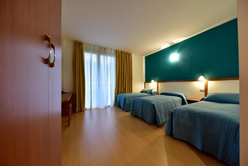 una habitación de hotel con 2 camas y una pared verde en Hotel La Pieve, en Pieve Vergonte