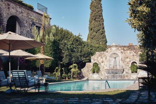 a pool with chairs and umbrellas next to a building at Casa de Sierra Nevada, A Belmond Hotel, San Miguel de Allende in San Miguel de Allende