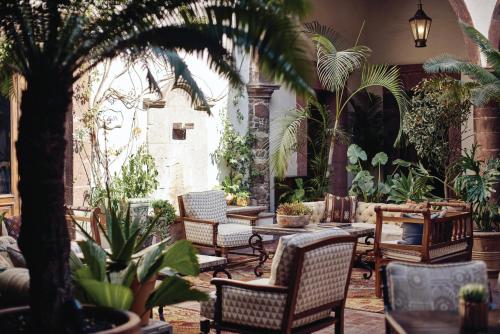 a patio with chairs and tables and plants at Casa de Sierra Nevada, A Belmond Hotel, San Miguel de Allende in San Miguel de Allende