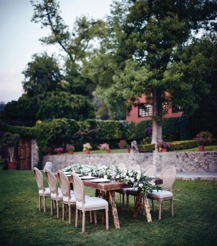 a wooden table with chairs and flowers on it at Casa de Sierra Nevada, A Belmond Hotel, San Miguel de Allende in San Miguel de Allende