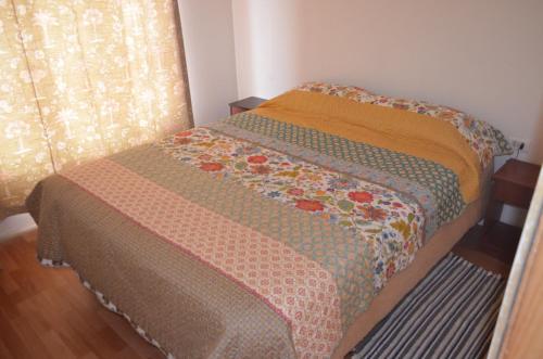 a bed with a quilt on it in a room at Cabaña Laynaturi in San Pedro de Atacama