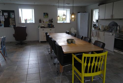 uma cozinha com uma mesa de madeira e cadeiras amarelas em Agervig Bed & Breakfast em Næsbjerg