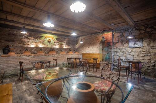a dining room with tables and chairs and a stone wall at Hotel Paradise Road in Kutaisi