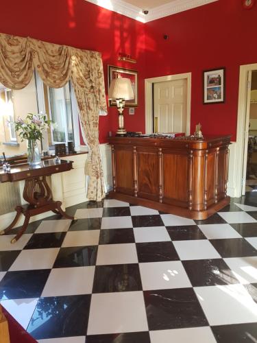 Cette chambre est dotée d'un sol en damier et de murs rouges. dans l'établissement The 19th Golf Lodge, à Ballybunion