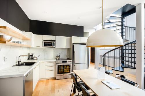 a kitchen with white cabinets and a table and a staircase at Les Lofts St-Pierre - Par Les Lofts Vieux-Québec in Quebec City