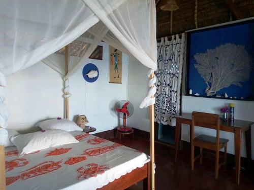 a bedroom with a bed and a desk and a bed and a bedskirts at Remo e Berenice in Nosy Komba