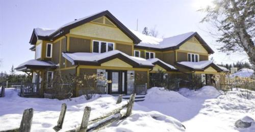a house covered in snow with a fence at Aiglon by Rendez-Vous Mont-Tremblant in Mont-Tremblant