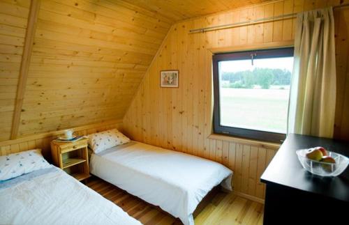 a bedroom with two beds in a wooden cabin at Domek letniskowy z kortem tenisowym Karwia Ostrowo in Ostrowo