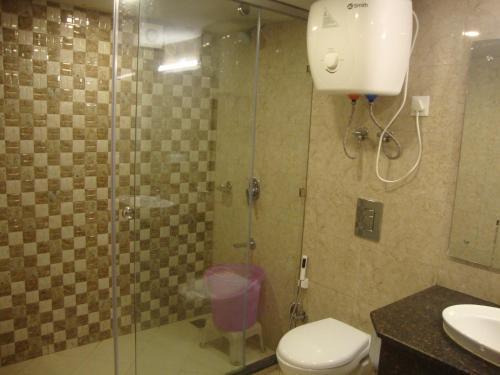a bathroom with a shower with a toilet and a sink at Hotel Hamers International in Mussoorie