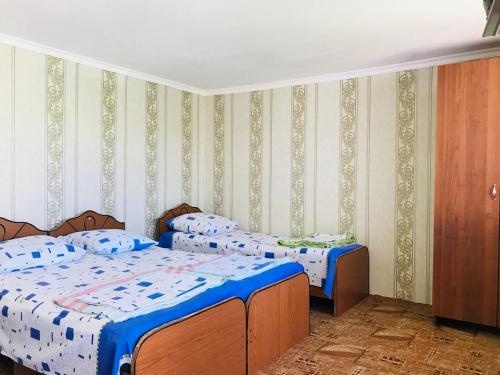 a bedroom with two beds with blue and white sheets at У Ханумы (Цандрипш) in Tsandrypsh