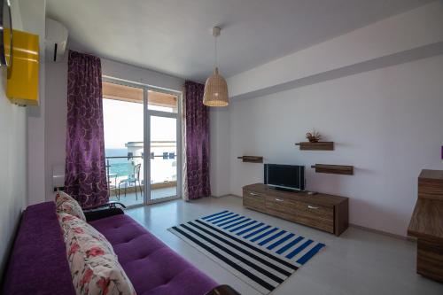 a living room with a purple couch and a tv at Apartamente Gala Residence Eforie Nord in Eforie Nord