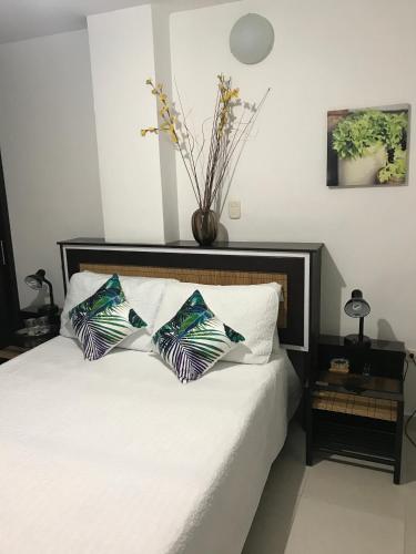 a bedroom with a white bed with two pillows at Hotel Meson de las Flores in Armenia