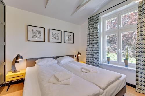 ソポトにあるSopot Comfort Apartments Superiorのベッドルーム1室(白いベッド1台、窓2つ付)