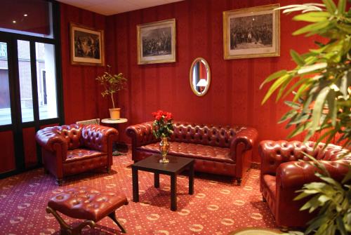 a living room with leather couches and a table at Hôtel 1er Consul Rouen in Rouen