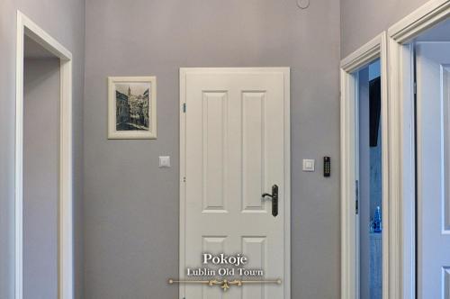 a white door with a sign on it in a hallway at Lublin Old Town Rooms in Lublin