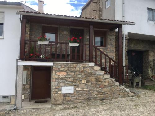 a stone house with a balcony with flowers on it at Casa Freixedelo in Santa Comba de Rossas