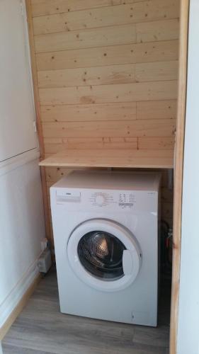 a washing machine in a room with a wooden wall at Gîte au pied des volcans d'Auvergne Aydat in Aydat