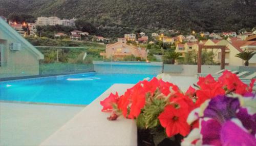 een vaas gevuld met rode bloemen op een tafel naast een zwembad bij Apartment Sun Village Goran in Herceg-Novi