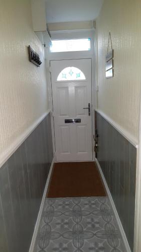 a small hallway with a white door with a window at Chinwin Cottage in Weymouth