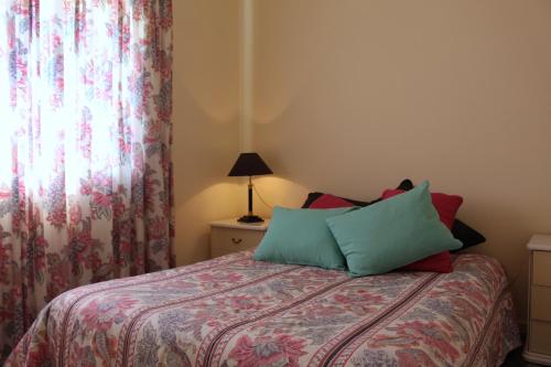 a bedroom with a bed with green and red pillows at Cozy Summer House by the Beach in Ovar