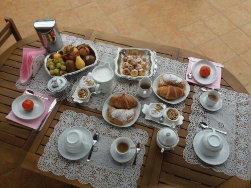 una mesa llena de alimentos para el desayuno y tazas de café en B&B Villa Sul Golfo, en Quartu SantʼElena