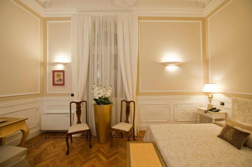 a bedroom with a bed and two chairs and a vase with flowers at Palazzo Lombardo in Florence
