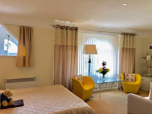 a bedroom with a bed and two chairs and a table at Arun Sands Rooms in Littlehampton