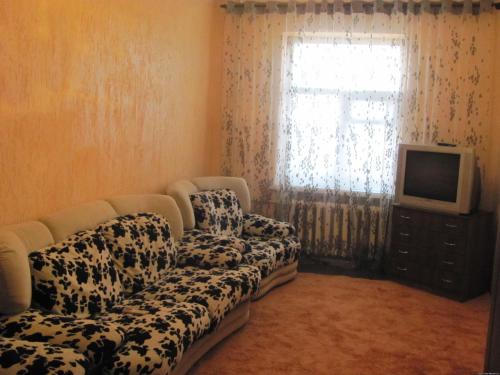 ein Wohnzimmer mit einem Sofa, einem TV und einem Fenster in der Unterkunft Letto UTZ in Mykolajiw