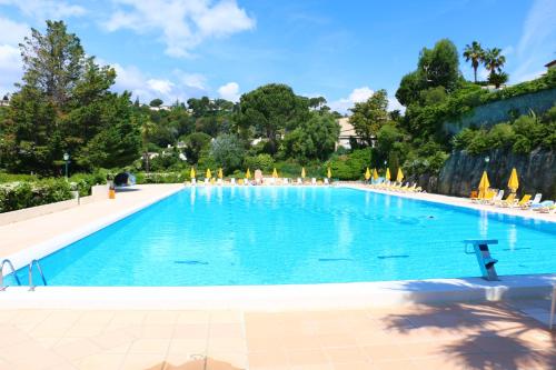 une grande piscine bleue avec des chaises et des arbres dans l'établissement French Riviera - Vaugrenier, à Villeneuve-Loubet