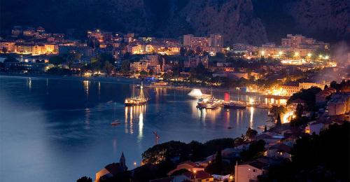 a view of a city at night with boats in the water at Mini stone house in Omiš
