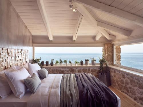 a bedroom with a large bed with a view of the ocean at Arismari Luxury Villas in Vasilikos