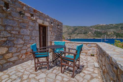 a patio with chairs and a table on a stone wall at Psamathous Guesthouse in Pórto Káyio