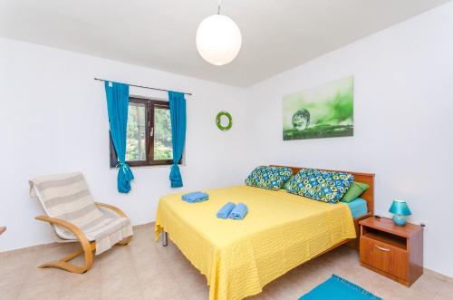 een slaapkamer met een geel bed en een stoel bij House Filip in Bogomolje