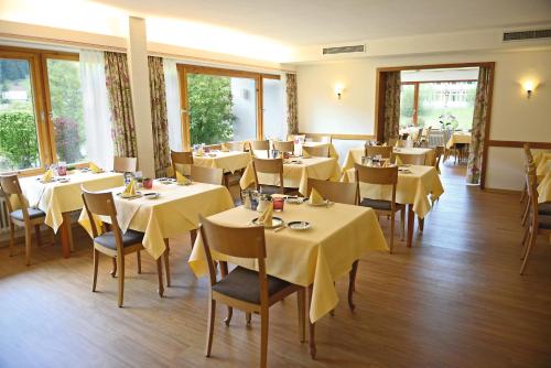 ein Restaurant mit Tischen und Stühlen mit gelbem Tischtuch in der Unterkunft Hotel Waldlust in Baiersbronn