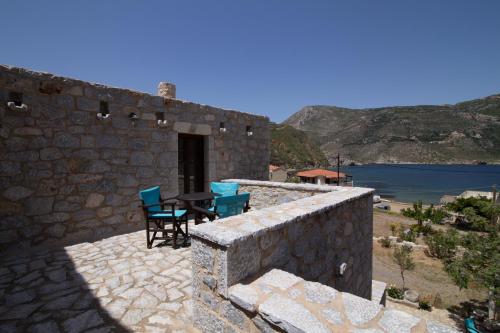 a patio with a table and chairs on a stone wall at Psamathous Guesthouse in Pórto Káyio