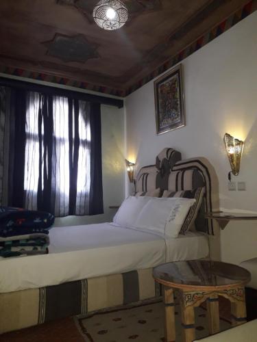 a bedroom with a bed and a table and a window at Hotel Anaia in Chefchaouene