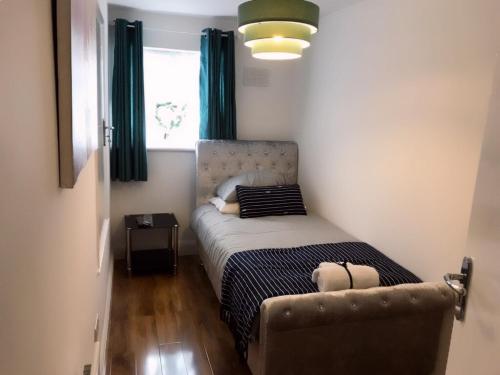 a small bedroom with a bed and a chair at Charimore Relaxation House in Abbey Wood
