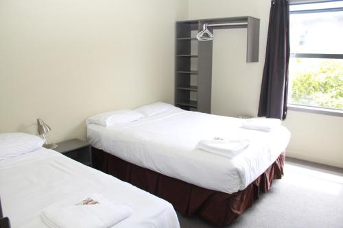 two twin beds in a room with a window at Nikau Apartments in Nelson